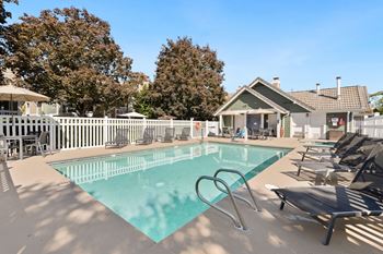 A swimming pool surrounded by lounge chairs and trees.